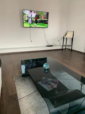 a living room with a table and a tv on the wall at Luxury Apartment Eleni in centre of Sandanski in Sandanski