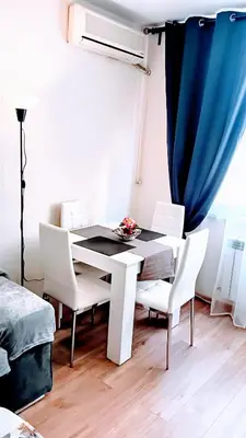 a dining room table with white chairs and a blue curtain at Doble next to Bulgaria mall, FREE underground parking in Sofia