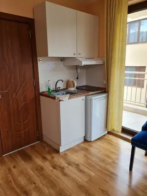 a kitchen with white appliances and a wooden floor at Cozy studio with balcony in Sofia