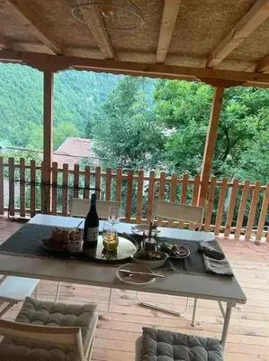 a table with a bottle of wine on a patio at Rodopi Mountain Village House in Narechen