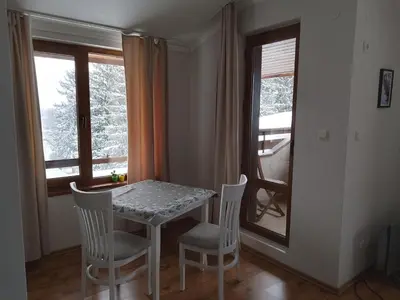 a table and chairs in a room with a window at Роси Студио Банско in Bansko