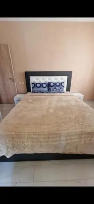 a bedroom with a large bed with a wooden headboard at Апартамент Недялкови II in Sandanski