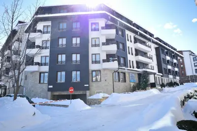 a snow covered street in front of a building at GT Aspen House Apartments in Bansko