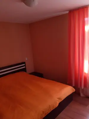 a bedroom with a bed and a window with red curtains at Easy rooms in Sapareva Banya