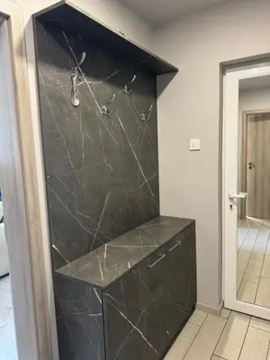a walk in shower with a black marble wall at West Park Apartment in Sofia