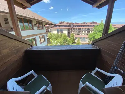 a balcony with two green chairs on a balcony at Cozy flat in NEON in Bansko