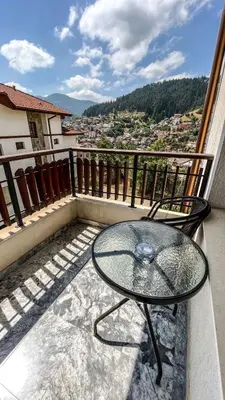 a glass table on a balcony with a view at Villa Orpheus in Chepelare