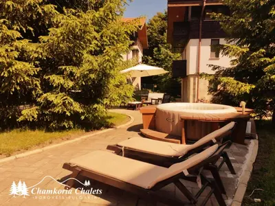a group of lounge chairs and a table with an umbrella at Chamkoria Chalets 409 in Borovets