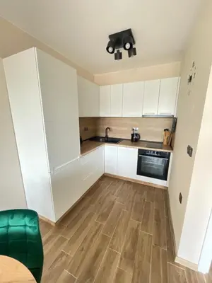 a kitchen with white cabinets and a wooden floor at Modern 1BR Apart FREE Parking with Hill View in Plovdiv