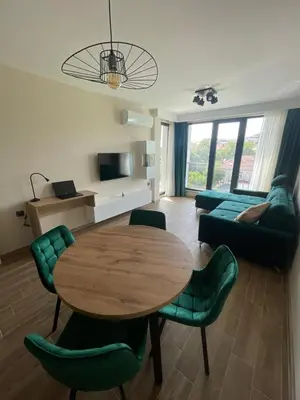 a living room with a wooden table and green chairs at Modern 1BR Apart FREE Parking with Hill View in Plovdiv