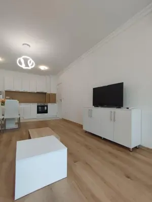 a large white room with a white table and a tv at Stylish apartment Zingara 2 in Sofia