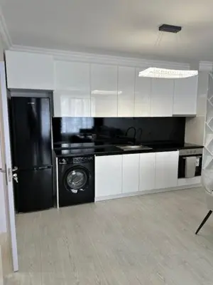 a kitchen with a black refrigerator and white cabinets at Danielis Apartament in Velingrad
