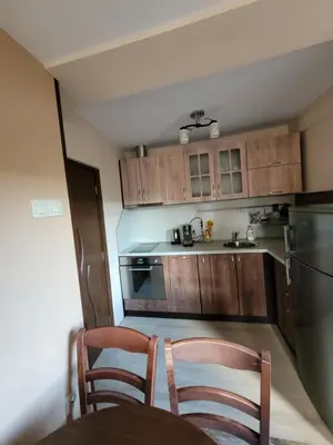 a kitchen with wooden cabinets and a table and chairs at Къща за гости ЕВА in Madzhare