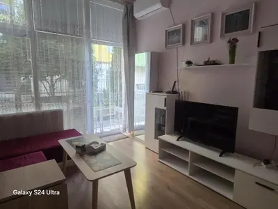 a living room with a couch and a tv and a table at Roses in Sofia