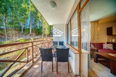 a room with a balcony with a table and chairs at MyPlace Pamporovo 2 in Pamporovo