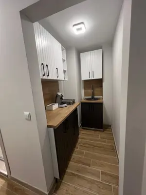 a kitchen with white cabinets and wooden floors at GREEN PARK Apartments and rooms for guests in Asenovgrad