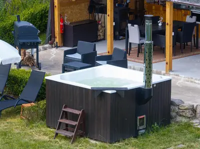 a hot tub sitting in the grass next to chairs at Kostenets Hills in Kostenets Village