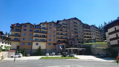 a large building with cars parked in a parking lot at Saphir apartment , Rhodopi Pearl Pamporovo in Pamporovo