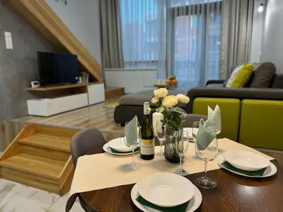 a living room with a table with wine glasses and flowers at Modern Vitosha Maisonette with Garage in Sofia