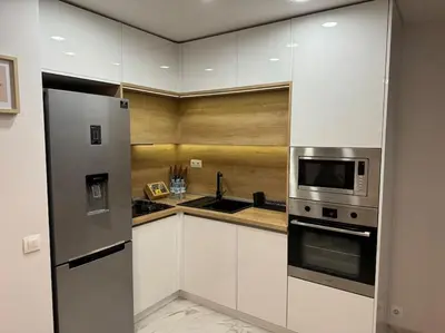 a kitchen with white cabinets and a stainless steel refrigerator at Modern Vitosha Maisonette with Garage in Sofia