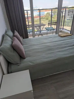a bed with pillows in a room with a balcony at Reina Apartment- next to Sofia zoo and close to Mall Paradise in Sofia