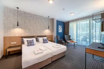 a hotel room with a large bed and a desk at Парк Хотел Модър in Devin