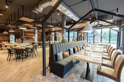 a restaurant with tables and chairs and windows at Парк Хотел Модър in Devin