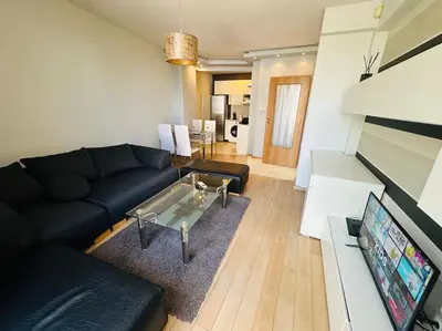 a living room with a black couch and a tv at Student Town 1BDR APT in Sofia