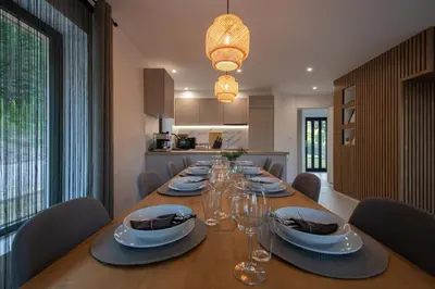 a dining room with a long table with plates and wine glasses at Hyggemate - Nordic Villa with Sauna & Jacuzzi Retreat in Sarnitsa