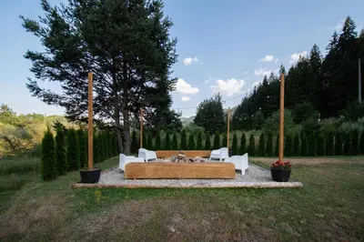 a bench in the middle of a field with two chairs at Hyggemate - Nordic Villa with Sauna & Jacuzzi Retreat in Sarnitsa