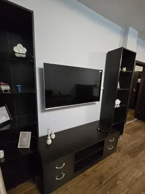 a black entertainment center with a flat screen tv on a wall at Lux apartment 223 in Bansko