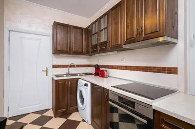 a kitchen with wooden cabinets and a dishwasher at 1BD flat with Desk on Russian Monument Square by Flat Mаnager in Sofia