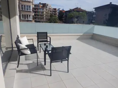 three chairs and a glass table on a roof at Sunshine terrace in Plovdiv