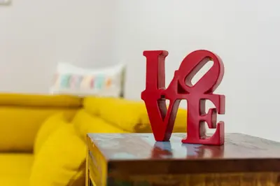 a red sign on a table in front of a yellow couch at Spacious Sofia Condo - Philadelphia LOVE in Sofia