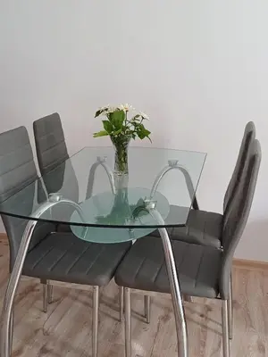 a glass table with two chairs and a vase with flowers at Апартамент Престиж 1 in Hisarya