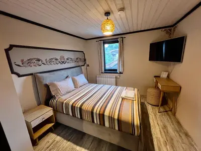 a small bedroom with a bed and a television at Китанова къща in Koprivshtitsa