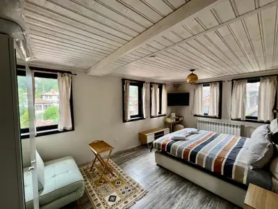 a bedroom with a bed and a couch and windows at Китанова къща in Koprivshtitsa