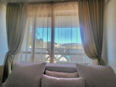 a living room with a couch and a large window at Апартамент А101 хотел Снежанка in Pamporovo