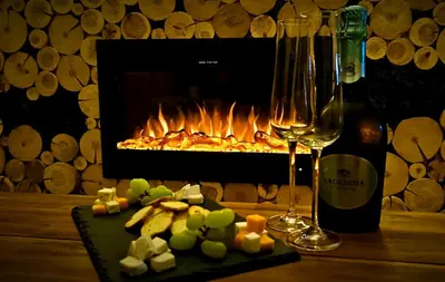 a table with a bottle of wine and a plate of food and a fireplace at Wooden Paradise Apartment next to Gondola in Bansko