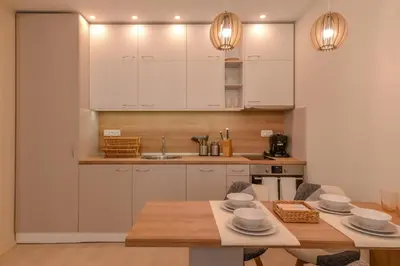 a kitchen with white cabinets and a wooden table at Elegant 1BD Stay on Ekzarh Yosif, Sofia by Flat Mаnager in Sofia