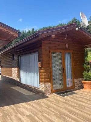 a log cabin with a large door on a wooden deck at SAFI FOREST village in Dospat