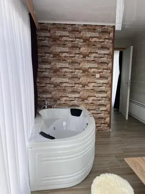 a bath tub in a bathroom with a brick wall at SAFI FOREST village in Dospat