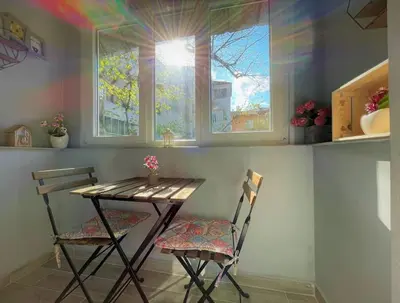 a table and chairs in a kitchen with two windows at Apartment in the Top center next to NDK in Sofia