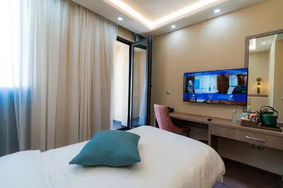 a bedroom with a bed and a desk with a television at Aurora Sofia in Sofia
