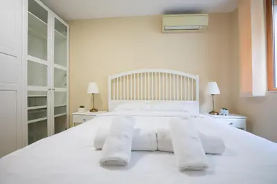 a white bed with two white towels on it at Bright 1BDR Apartment in Top Center in Sofia