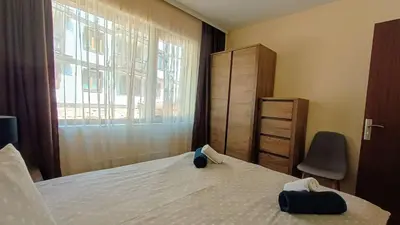 a bedroom with a bed and a chair and a window at Kandahar Private Apartments in Bansko