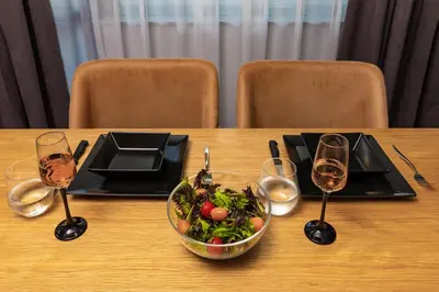 a table with a bowl of salad and glasses of wine at Happy People Plovdiv - Grey 1-BD Apartment by Flat Mаnager in Plovdiv