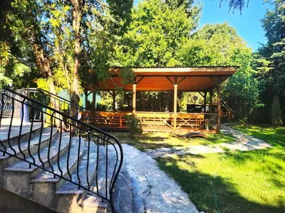 a wooden gazebo in a park with trees at Вила Княжеска баня in Sofia