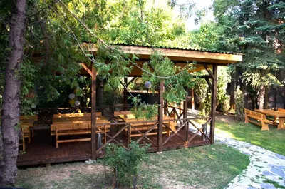 a wooden gazebo with wooden tables and benches at Вила Княжеска баня in Sofia