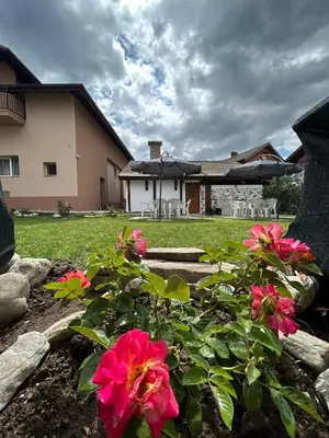 a garden with pink flowers in front of a house at Къща Цвети in Dobrinishte